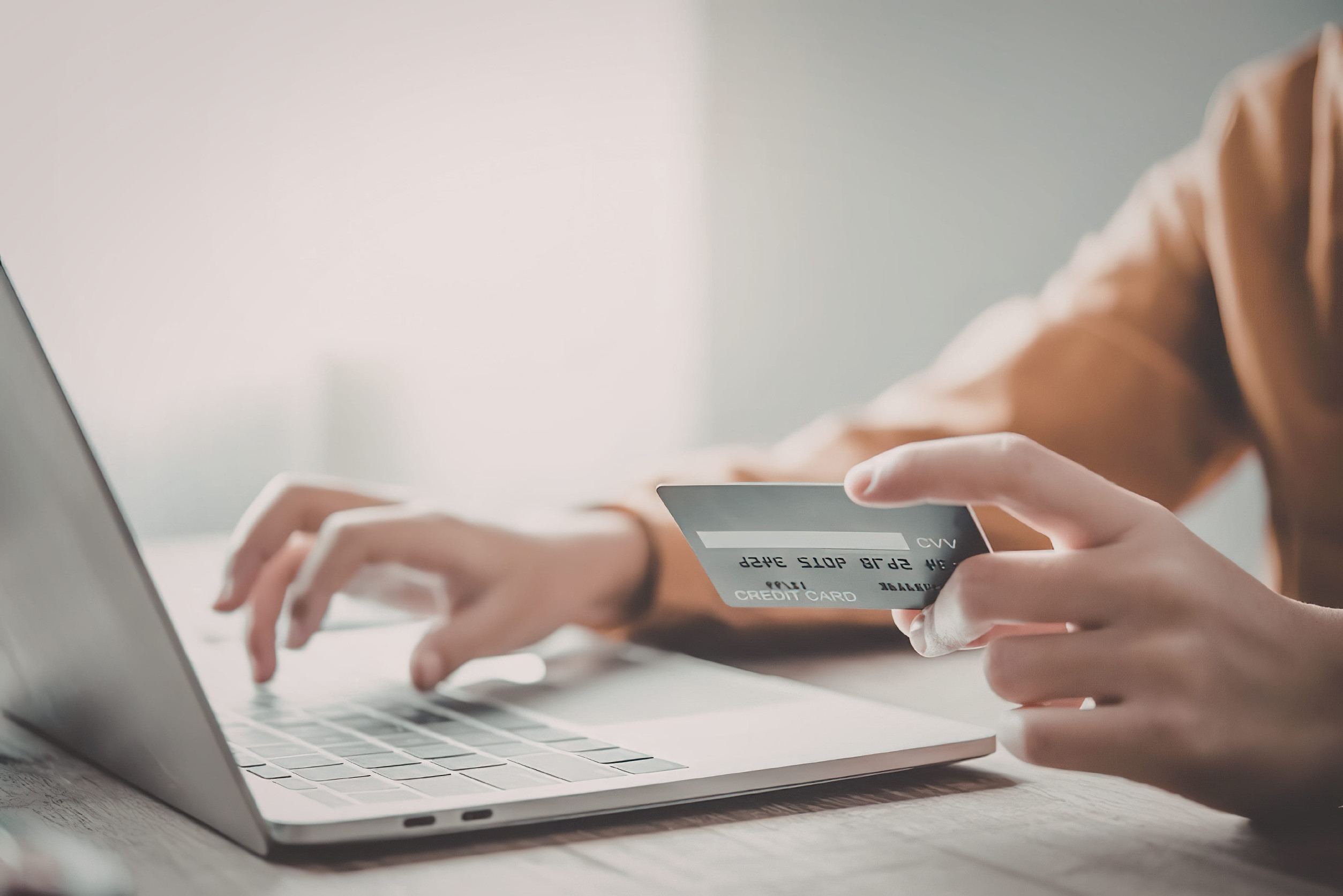 A man using a laptop and holding a credit card